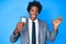 Handsome african american man with afro hair holding detective badge celebrating victory with happy smile and winner expression