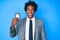 Handsome african american man with afro hair holding detective badge looking positive and happy standing and smiling with a