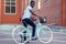 Handsome African American man stylish well-dressed standing with a blue bicycle red brick building background . sports