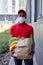 Handsome african delivery worker man in cap and medical mask carrying packet with fresh food