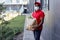 Handsome african delivery worker man in cap and medical mask carrying packet with fresh food