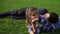Handsome african guy lying on the back of his caucasian girlfriend on the green field and talking. Multiethnic couple