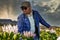 A handsome African man on a hiking trail in South Africa stop to look at pink King Protea flowers during spring time.