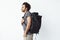 Handsome african man with rucksack standing in profile over white background.