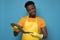 Handsome african serious guy in yellow apron holding in hand big fresh fish