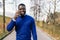 Handsome African youth in casual blue sweater, beaming smile and glasses, chatting on phone in well-lit park