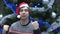 Handsome Aggressive Man Wearing Santa Hat and Is Shaking his Fist on Christmas Tree Background.