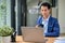 A handsome Asian businessman focuses on his work on his laptop while sipping coffee