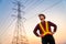 Handsome asian electrical engineer standing at high voltage pylon, Electricity generation concept