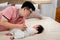 Handsome Asian father wearing pink shirt, Lying and teasing with his baby daughter, on a soft brown bed, The father gently invites