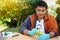 Handsome Asian man science teacher holds magnifying glass to inspect flowers.