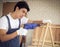 Handsome Asian repairman standing in wood workshop with white brick wall , holding drill in working with wooden frame