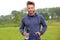 Handsome athlete standing outside in park with water bottle