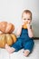 Handsome baby in denim overalls and pumpkin. Complementary feeding of children, first autumn of toddler, Halloween, food allergies