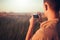 Handsome back view of a young man with vintage camera, on sunset and field background. Autumn mood and summer mood.