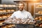 Handsome baker holding tray full of freshly baked croisants