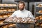 Handsome baker holding tray full of freshly baked croisants