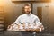 Handsome baker holding tray full of freshly baked croisants