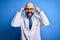 Handsome bald doctor man with beard wearing glasses and stethoscope over blue background Smiling pulling ears with fingers, funny