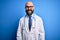 Handsome bald doctor man with beard wearing glasses and stethoscope over blue background winking looking at the camera with sexy