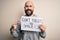 Handsome bald man with beard holding banner with funny positive message very happy pointing with hand and finger