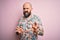 Handsome bald man with beard and tattoo wearing casual floral shirt over pink background disgusted expression, displeased and