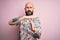 Handsome bald man with beard and tattoo wearing casual floral shirt over pink background Doing time out gesture with hands,