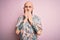 Handsome bald man with beard and tattoo wearing casual floral shirt over pink background laughing and embarrassed giggle covering