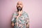 Handsome bald man with beard and tattoo wearing casual floral shirt over pink background Thinking concentrated about doubt with