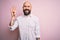 Handsome bald man with beard wearing elegant shirt over isolated pink background showing and pointing up with fingers number four