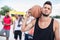 Handsome basketball player with ball on shoulder standing on court