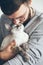 Handsome beard man is holding and kissing little Devon Rex cat.