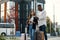 Handsome bearded african american guy and asian pretty girl gathering on business trip with suitcases waiting at stop.