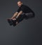 Handsome bearded athlete in sportswear jumping in a studio.