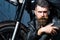 Handsome bearded biker in leather jacket sitting near motorcycle in garage