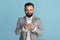 Handsome bearded entrepreneur searching web for business data on blue background