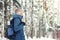 Handsome bearded male hiker in warm clothes with backpack and thermos travel in winter snowy forest. Seasonal outdoor travel