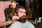 Handsome bearded man at barber shop. Hairstylist serving client at barbershop. Time for new haircut. Making haircut look perfect.