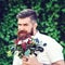 Handsome bearded man with beautiful bouquet of flowers. Wedding bouquet. Stylish bearded guy holding flowers outdoors. Wedding day