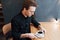 Handsome bearded man in checked shirt holding fork eating in cafe and smiling