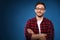 Handsome bearded man in glasses and red shirt Isolated on a dark blue background is thinking and smiling