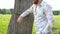 Handsome bearded man is leaning on tree in a field