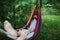 Handsome bearded man relaxing in hammock in shade in summer green garden