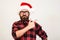 Handsome bearded man in Santa hat and glasses. Santa man pointing to the side over white wall. Christmas concept. Mock up, copy