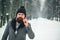 Handsome bearded man standing outdoors in winter. Confident brutal guy wearing fashion coat and knitted hat