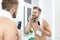 Handsome bearded man trimming his beard with a trimmer