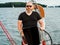 Handsome bearded person steering wheel sailboat on a lake in a cloudy summer day