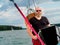 Handsome bearded person steering wheel sailing yacht on a lake in a cloudy summer day