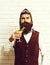 Handsome bearded pilot man with long beard and mustache on serious face holding glass of alcoholic cocktail in vintage