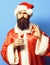 Handsome bearded santa claus man with long beard on funny face holding glass of alcoholic shot in red christmas or xmas